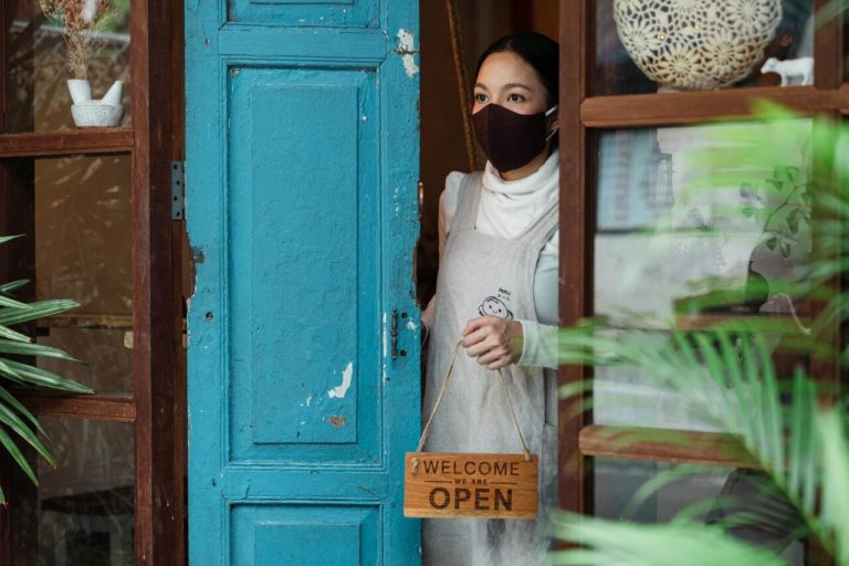 small-business-owner-opening-door-with-mask